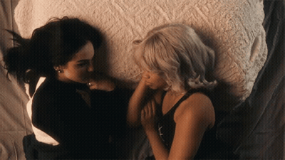 Two Women Laying On Bed Looking At Each Other GIF
