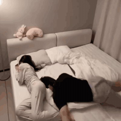 Two Women Laying On Bed With Stuffed Rabbit GIF