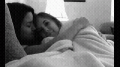 Two Women Laying On Couch Hugging And Kissing GIF