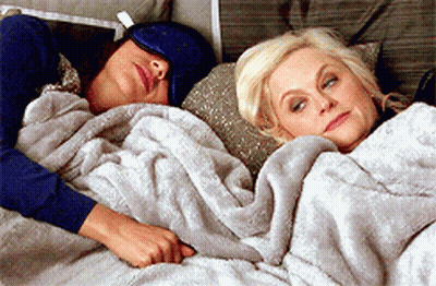 Two Women Lying In Bed Under Blanket GIF