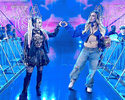 Two Women Making Heart Shape In Front Of Lexa Blitz Sign GIF