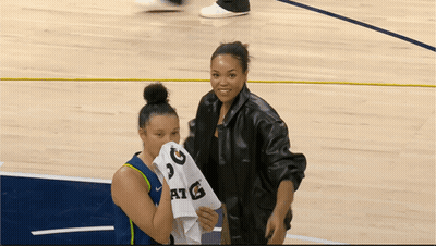 Two Women On A Basketball Court With One Holding A Shirt That Says Atg GIF