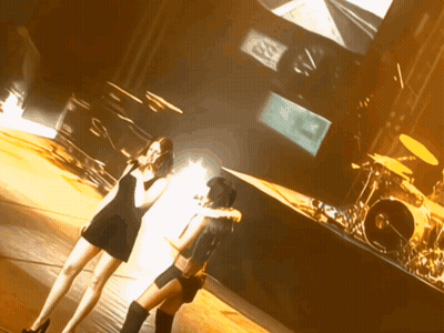 Two Women On Stage With Drum Set And SD Screen GIF