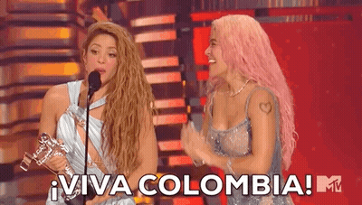 Two Women On Stage With Microphone And Trophy GIF