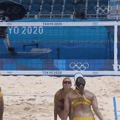 Two Women Playing Beach Volleyball In Front Of A Tokyo 2020 Sign GIF