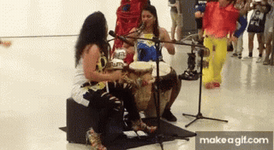 Two Women Playing Drums And Singing Into Microphones GIF