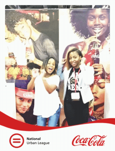 Two Women Posing In Front Of Coca Cola Ad GIF