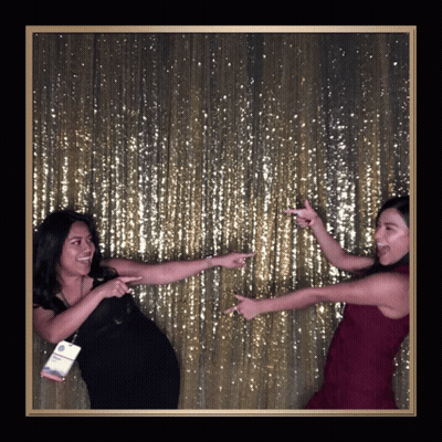 Two Women Posing In Front Of Gold Sequined Wall GIF