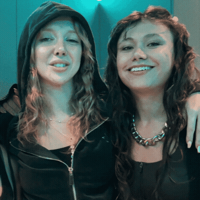 Two Women Posing, One In Black Hoodie GIF