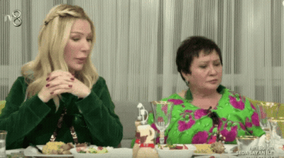 Two Women Sit At A Table With Plates Of Food And A Sign That Says Seda Sayan Ile On It GIF