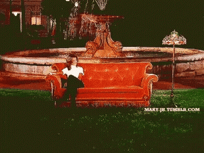 Two Women Sit On A Couch In Front Of A Fountain GIF