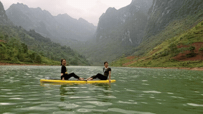 Two Women Sit On A Paddle Board In A Lake GIF
