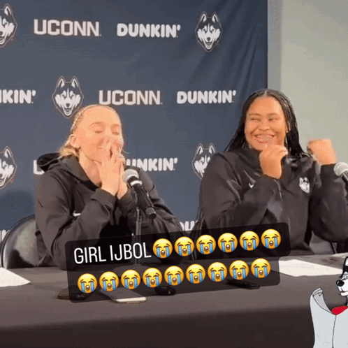 Two Women Sitting At A Table With A Sign That Says Girl Ijbol On It GIF