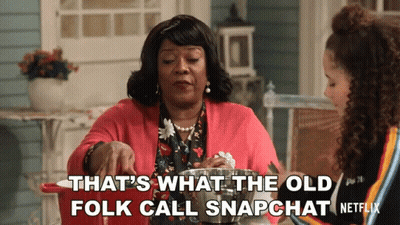 Two Women Sitting At A Table With The Words That 'S What The Old Folk Call Snapchat Written On The Bottom GIF