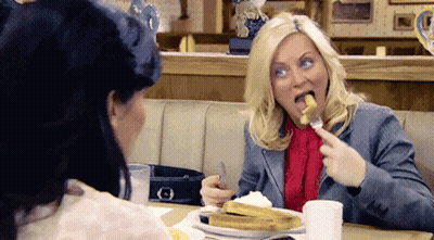 Two Women Sitting At Table Eating French Fries GIF
