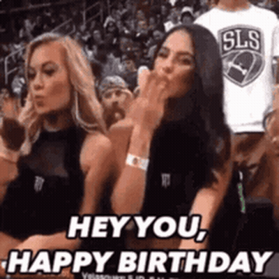 Two Women Sitting In Basketball Stands One Blowing A Kiss GIF