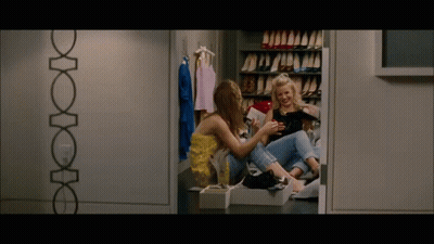 Two Women Sitting In Closet Looking At Tablet GIF