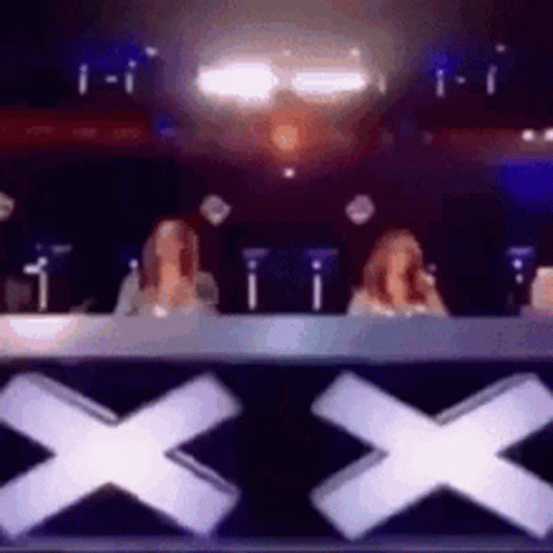 Two Women Sitting In Front Of X Sign GIF