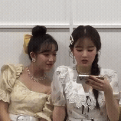 Two Women Sitting Looking At Phones GIF