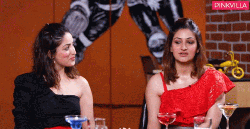Two Women Sitting Next To Each Other In Front Of A Pinkvilla Sign GIF
