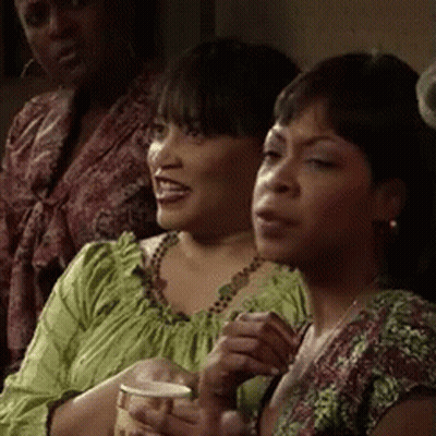 Two Women Sitting Next To Each Other One Holding Cup GIF