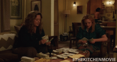 Two Women Sitting On A Couch Counting Money With The Kitchen Movie Written On The Bottom GIF