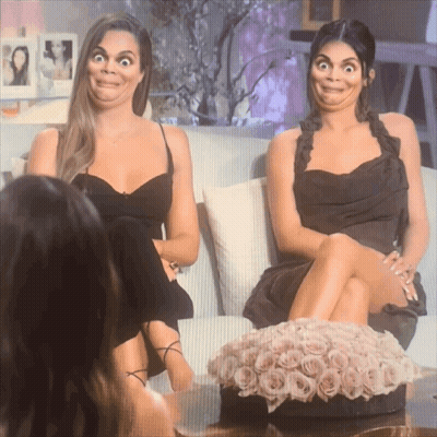 Two Women Sitting On A Couch With Their Legs Crossed Making Funny Faces GIF