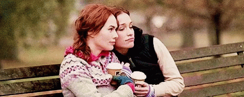 Two Women Sitting On Bench Holding Coffee GIF