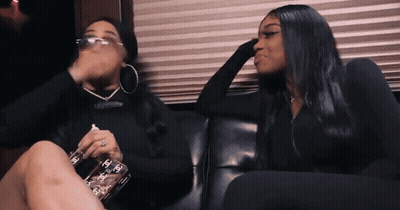 Two Women Sitting On Couch One Holding Chanel Bottle GIF