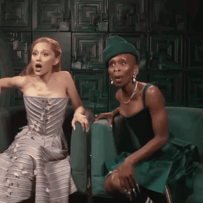Two Women Sitting On Green Couch GIF