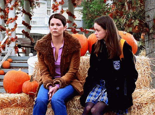 Two Women Sitting On Hay Bale With Pumpkins And Chester Patch GIF
