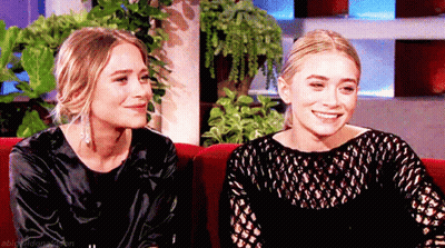 Two Women Sitting On Red Couch GIF