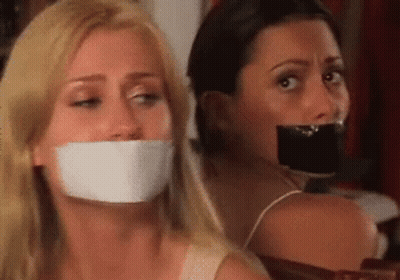 Two Women Sitting With Mouths Taped GIF