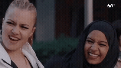Two Women Smiling And Laughing In Front Of M+ Sign GIF