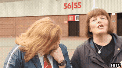 Two Women Standing In Front Of A Building With 56/55 On It GIF