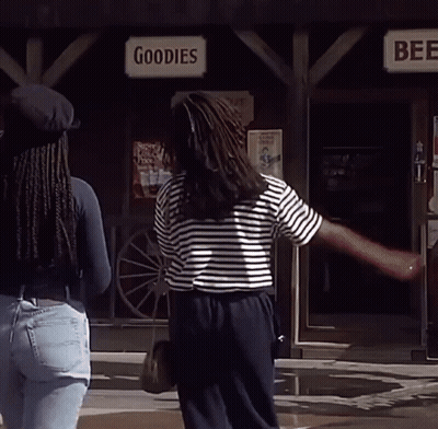 Two Women Standing In Front Of A Store Called Goodies And Beer GIF