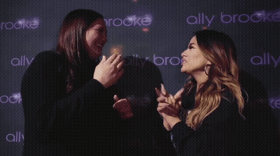 Two Women Standing In Front Of Ally Brooke Wall GIF