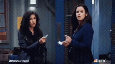 Two Women Standing In Front Of Blue Door Holding Paper GIF