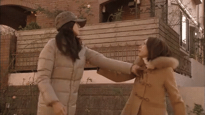 Two Women Standing In Front Of Building GIF