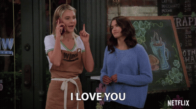 Two Women Standing In Front Of Netflix Sign GIF