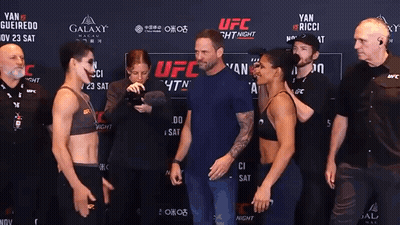 Two Women Standing In Front Of UFC Sign GIF