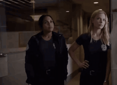 Two Women Standing In Hallway Looking At Something GIF