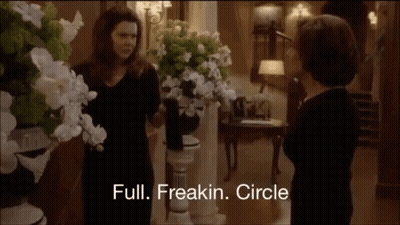 Two Women Standing Near Flowers GIF