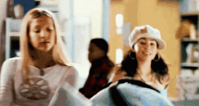 Two Women Standing Next To Each Other In A Room GIF