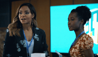 Two Women Standing Next To Each Other In Front Of A Sign That Says ' Jl ' On It GIF