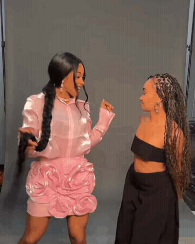 Two Women Standing Next To Each Other One In A Pink Dress And The Other In A Black Dress GIF