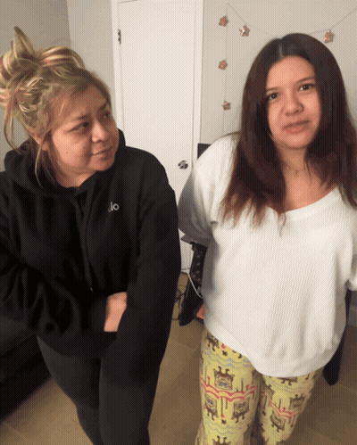 Two Women Standing Next To Each Other One Wearing A Black Hoodie With The Letter O On It GIF