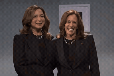 Two Women Standing Next To Each Other Wearing Black Suits GIF