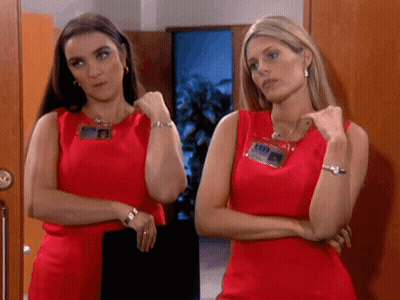 Two Women Standing Next To Each Other Wearing Red Dresses GIF