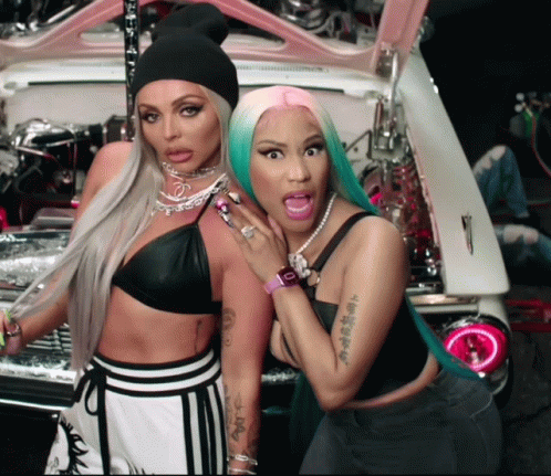 Two Women Standing Next To Each Other With One Having A Tattoo On Her Arm GIF